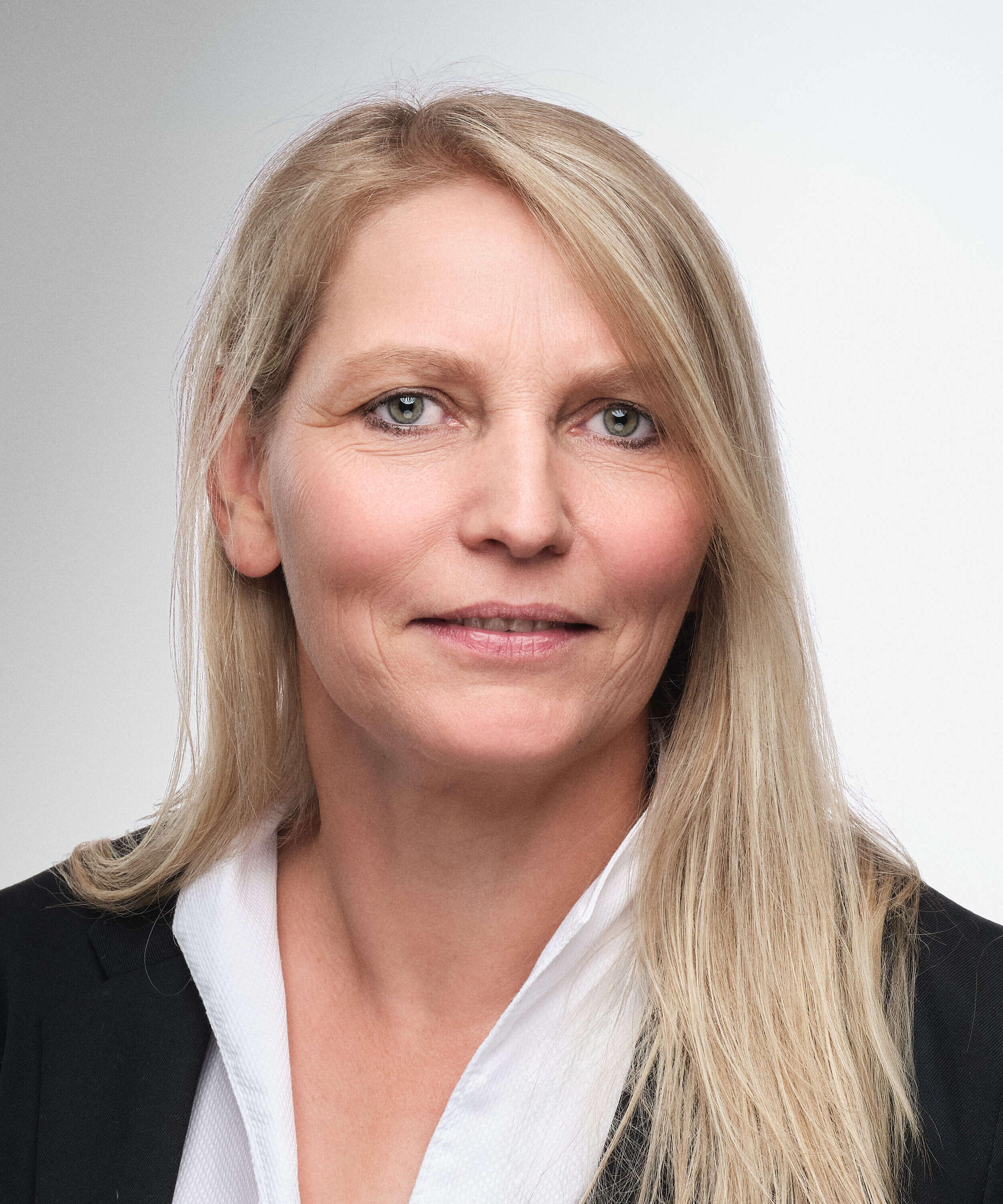 Eine weibliche Person mit blonden Haaren und schwarzer Jacke.